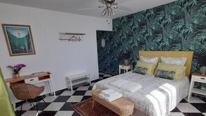Ein Schlafzimmer mit Schachbrettmuster Boden, einem Bett mit vielen Kissen, einer hängenden Deckenleuchte, einem an der Wand montierten Heizkörper und einem Poster an der Wand.
