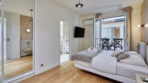 A modern bedroom with a large bed, a TV mounted on the wall, and a sliding glass door leading to a balcony with outdoor seating. - Terrace Apartment Trocadero Eiffel Tower (Paris)