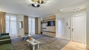 A modern living room with a sofa, coffee table, and a TV stand. - Terrace Apartment Trocadero Eiffel Tower (Paris)