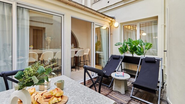 A sunlit patio with a dining table, chairs, and lounge chairs. - Terrace Apartment Trocadero Eiffel Tower (Paris)