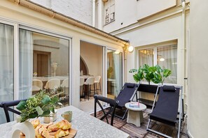 Une terrasse ensoleillée avec une table à manger, des chaises et des fauteuils de relaxation.