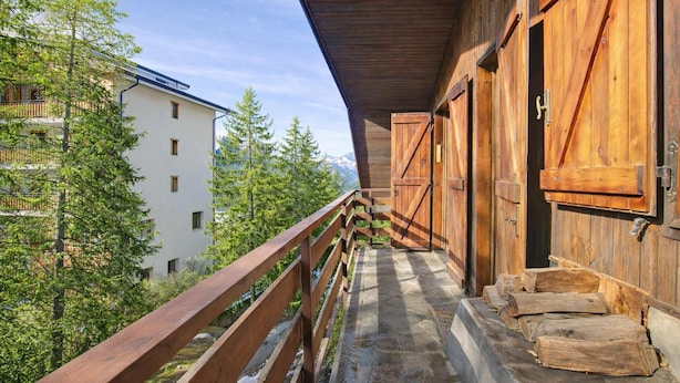 A wooden balcony with a railing, wooden doors, and a view of trees and a building. - Appartamento Beau Soleil ski in ski out (Sauze d'Oulx)