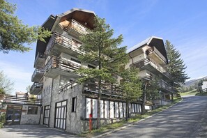 A modern multi-story building with balconies, a stone facade, and a clear sky.