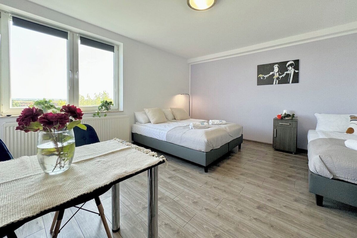A modern bedroom with a bed, bedside table, and a window.