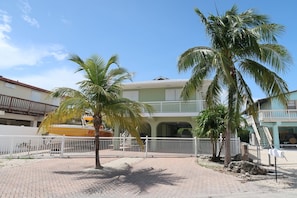 Enjoy stunning ocean views from the upper-level balcony of this beachfront property, surrounded by palm trees and an entrance.