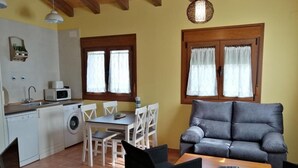Um espaço compacto com cozinha compacta, área de refeições e sala de estar com sofá e cadeiras.