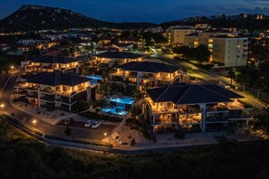 A multi-story hotel with a swimming pool, located in a residential area with surrounding houses.