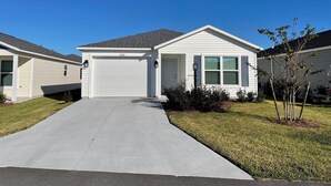 A single-story house with a garage, a front yard, and a clear blue sky. - Cozy Retreat Near Sawgrass Market & Brownwood Paddock Square! (Wildwood)