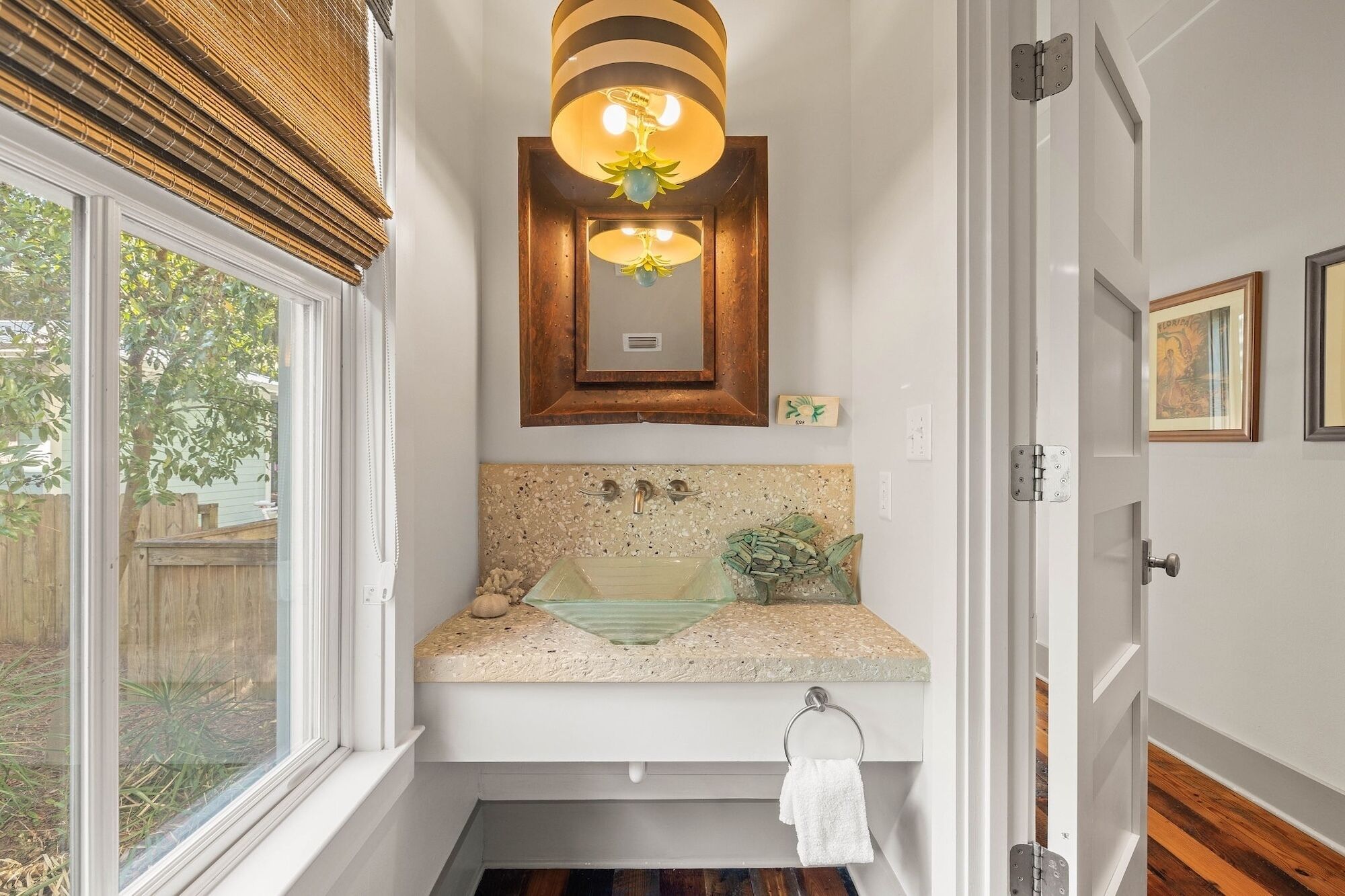 A bathroom with a window, a sink with a decorative backsplash, a towel rack, and a wooden door.