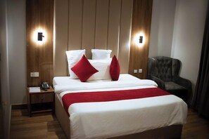 A hotel room with a bed, a nightstand, a telephone, and a chair. - Favourite Hotel (Lagos)