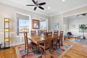 Enjoy meals in this dining area with a large table and six chairs, surrounded by large windows offering views of the outdoors.