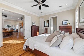 Relax in this serene bedroom with a large bed, ceiling fan, and wooden dresser.