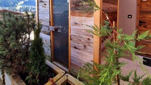 A wooden cabin with a balcony, a sliding glass door, and a view of the surrounding landscape. - Apartment Lumikki |  Private hot tub and sauna (Les Gets)