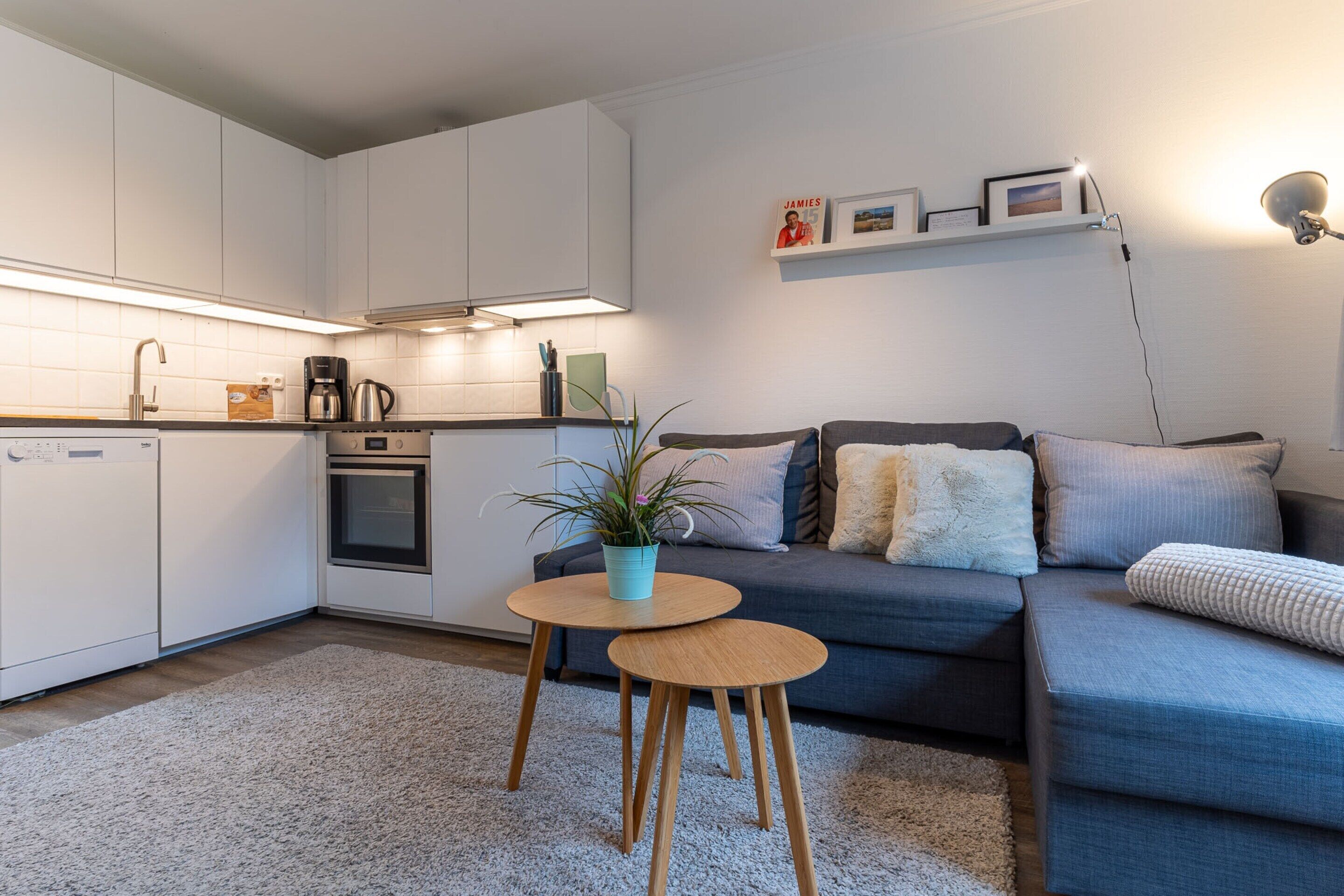 A modern kitchen with white cabinets, a coffee maker, and a small table with a plant.