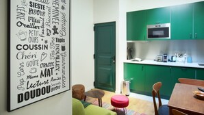 Una cucina moderna con mobili verdi, un forno a microonde e un piccolo angolo ristoro con tavolo e sedie.