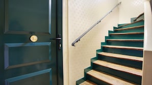 Una scala con gradini in legno e un corrimano in metallo, che conduce a una porta con pomello in ottone.