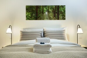 A neatly made bed with a folded towel and two glasses, flanked by two lamps and a forest-themed wall hanging. - Sublim and New Duplex Le Marais/beaubourg (Paris)