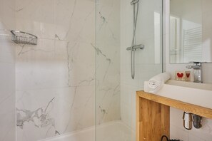 A bathroom with a glass-enclosed shower, a wooden vanity, and a marble-tiled wall. - Sublim Apartement Saint Germain des Pres (Paris)