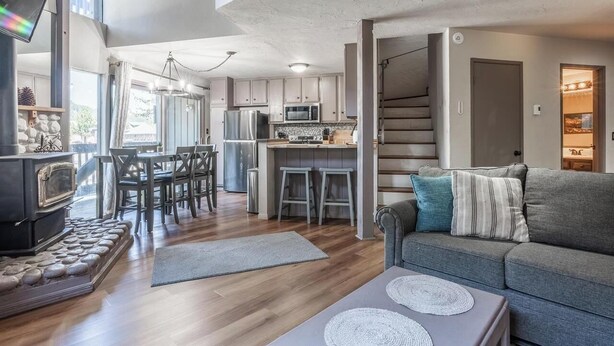 A modern kitchen with a central island, a dining area with chairs, a sofa, and a fireplace.