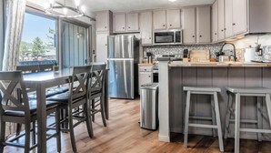 A modern kitchen with a central island, stainless steel appliances, and a view to the outside.