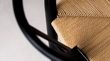 Primer plano de una silla con asiento tejido y estructura de metal negro.
