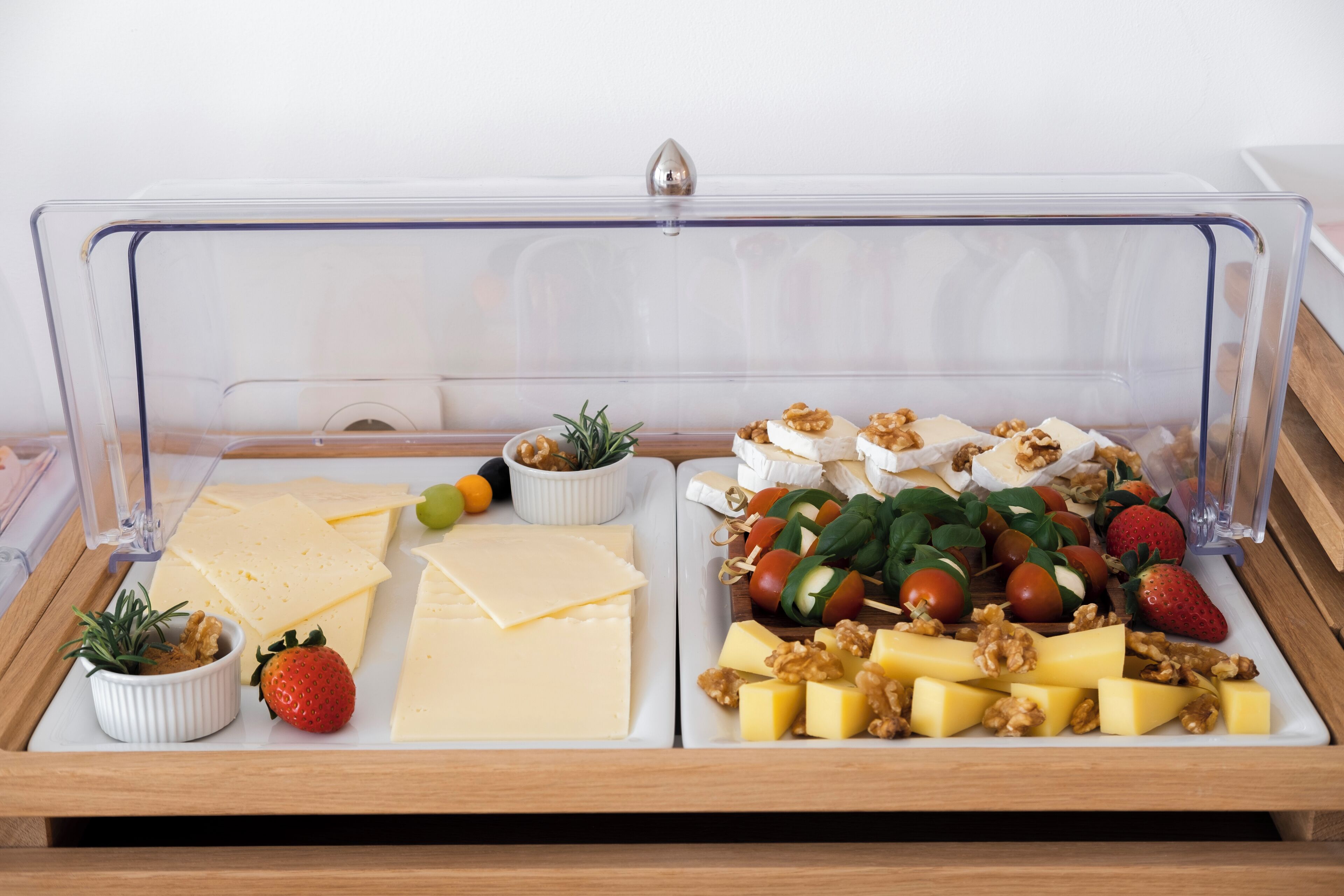 A food display with various cheeses, fruits, and nuts.
