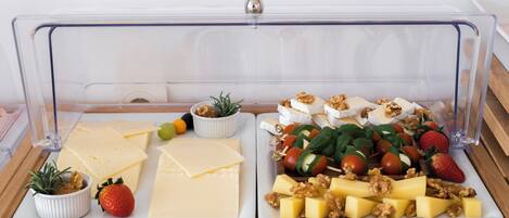 A food display with various cheeses, fruits, and nuts.
