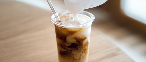 A clear glass cup with ice cubes and a straw, placed on a wooden surface.