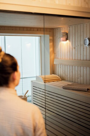 Un cuarto de sauna con un banco de madera, una toalla y un calentador en la pared.