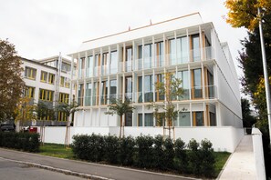 Un edificio moderno con varios pisos, ventanas amplias y fachada blanca.