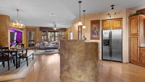 A spacious kitchen with wooden cabinets, a stainless steel refrigerator, and pendant lighting. - *NEW* Mooseberry Villa • King Bed • eBikes • Nearby Fool Hollow Lake • Torreon (Show Low)