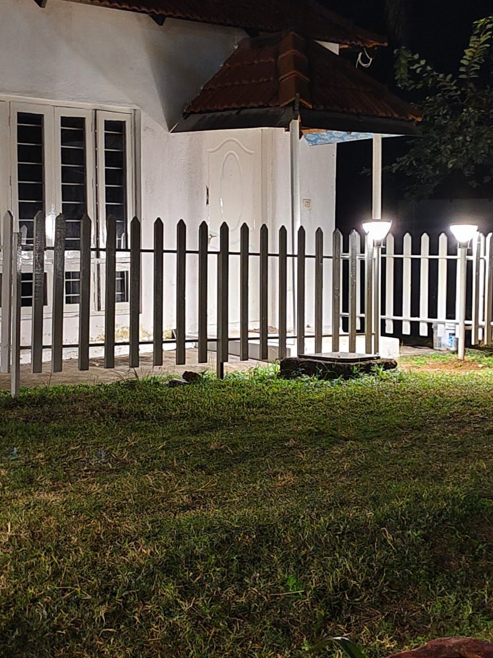 Edifici blanc amb un pati tancat de nit, il·luminat per fanals.