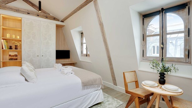 Une chambre à coucher avec un lit, une table de chevet et une fenêtre avec des rideaux.