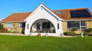 A house with a white exterior, a tiled roof, and a large arched window.