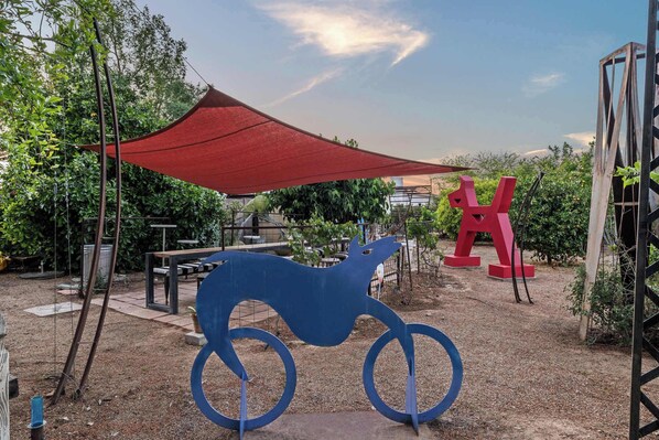 A garden with a red canopy, a blue sculpture of a horse, and red letter sculptures.