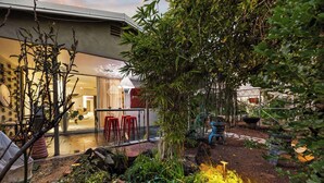 Een modern huis met een glazen deur die leidt naar een eethoek met rode krukken.