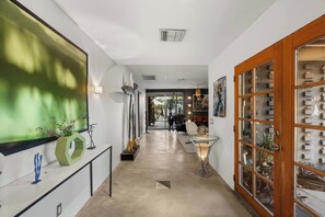 A hallway with a modern design, featuring a glass display case on the right and a large abstract painting on the left. - Experience Jeff Zischke's Cholla 64 Compound (Scottsdale)