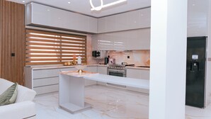 A modern kitchen with a built-in oven, microwave, and a coffee machine.