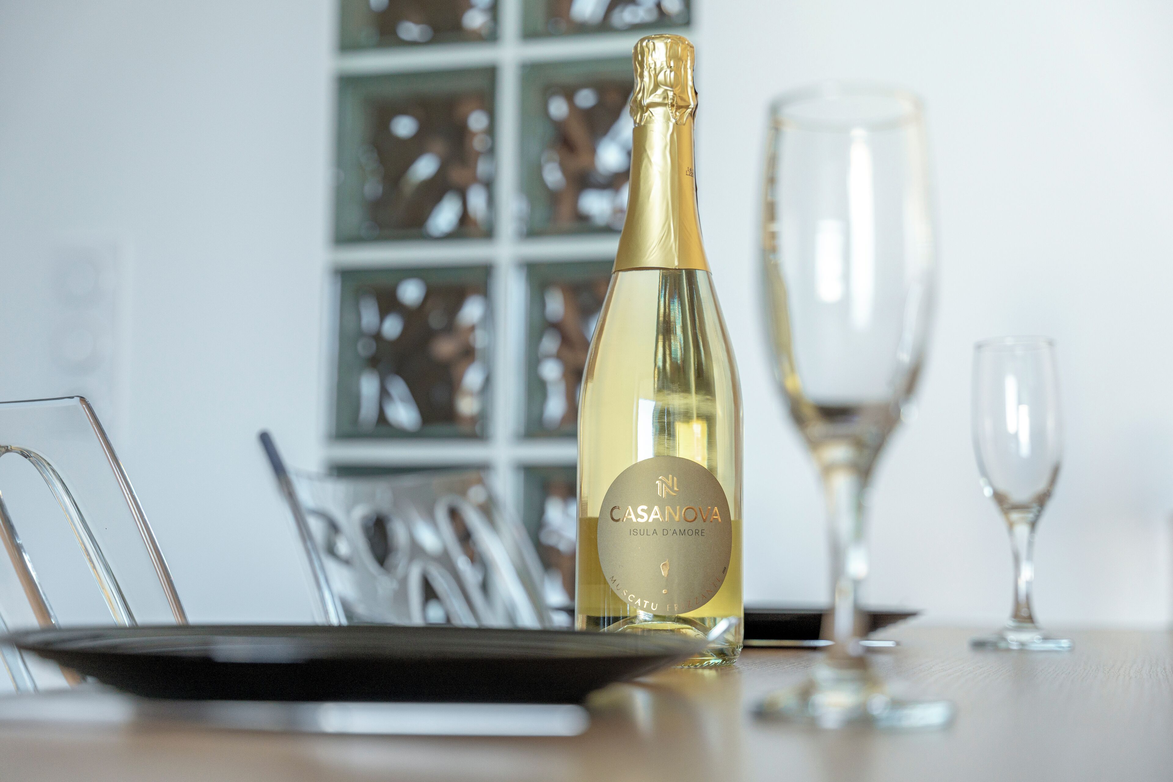 A bottle of Casanova wine on a table with a glass and a plate.