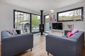 A modern living room with two grey sofas, a TV, artwork, and a fireplace.