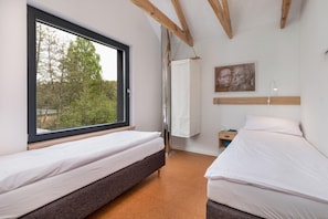 Un dormitorio con dos camas, una ventana, un cuadro y una mesita de noche.