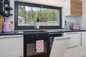 Una cocina moderna con ventana, hervidor, tostadora y lavavajillas.
