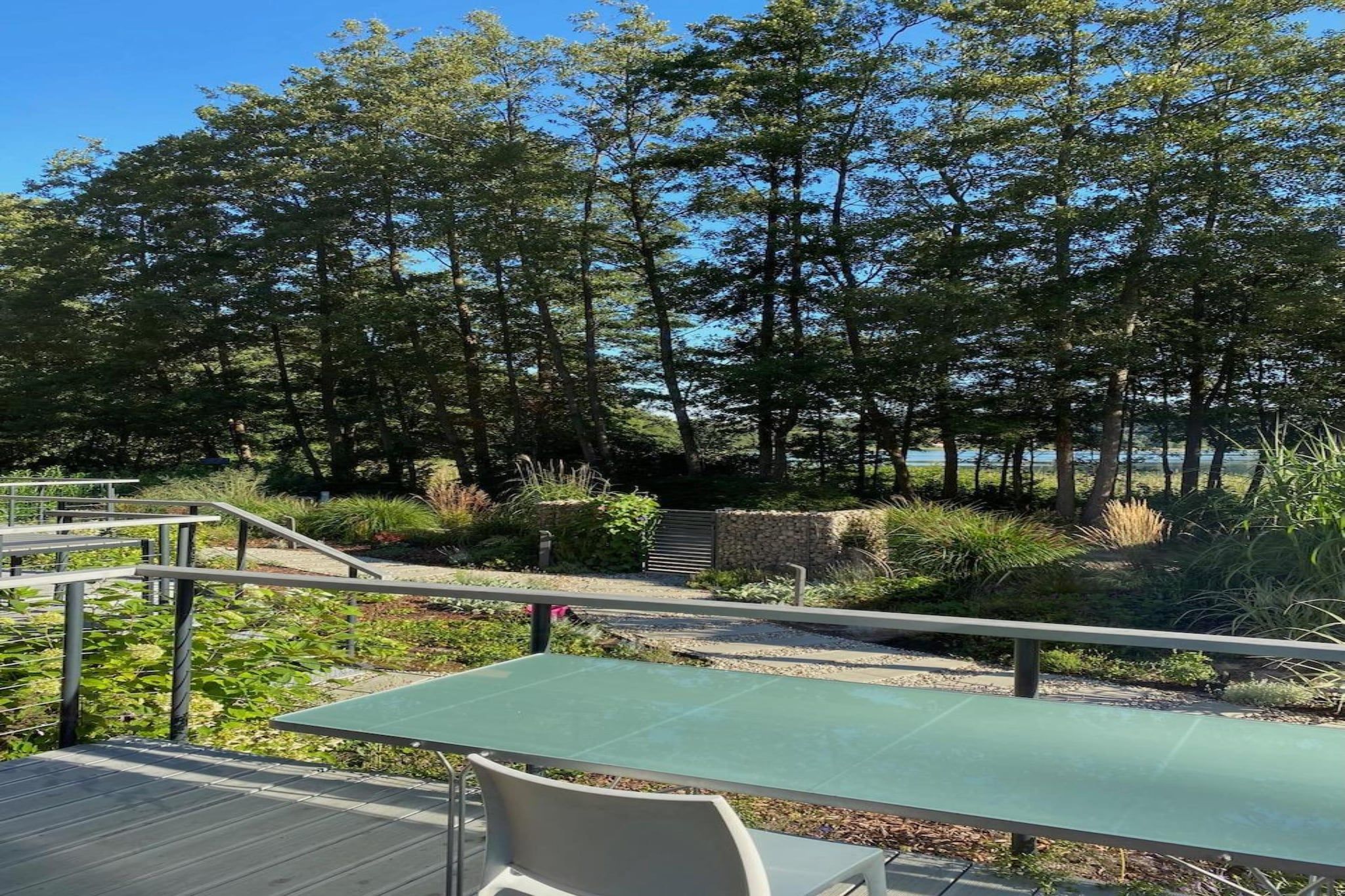 An outdoor area with a table and chairs, surrounded by trees and a stone wall.