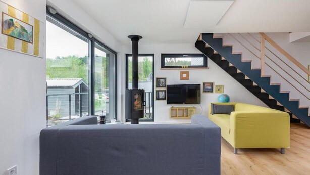 A modern living room with a sofa, a television, and a fireplace. - Holiday Home by Lake Wisełka with Sauna (Wiselka)