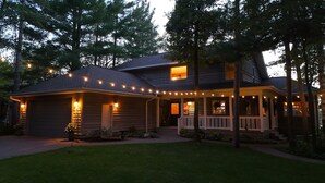 Una casa de dos pisos con un porche y luces colgantes.
