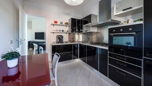 A modern kitchen with black cabinets, stainless steel appliances, and a white ceiling light. - Vaticano84 Gemelli (Rome)