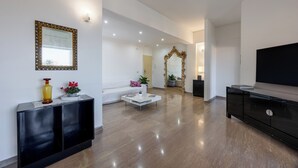 A modern living room with a white sofa, a coffee table, a black console table, and a large mirror. - Vaticano84 Gemelli (Rome)