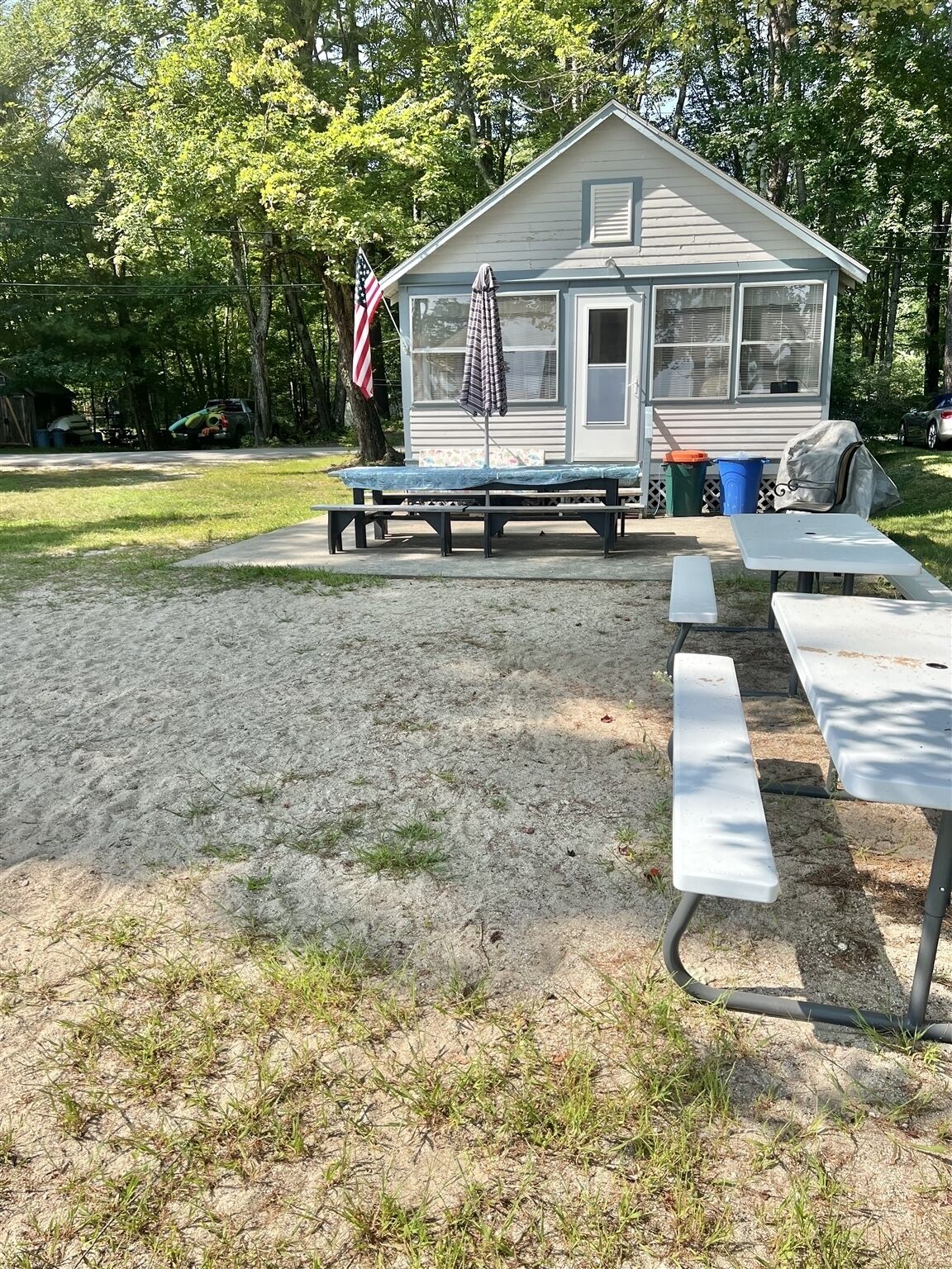 Una cabaña pequeña con una mesa de picnic y bancos al frente.