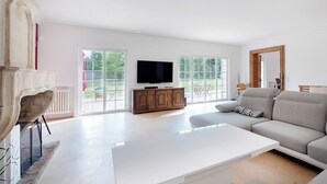 Un soggiorno ampio con un tavolino da caffè bianco, un divano grigio e una televisione su un mobile in legno.