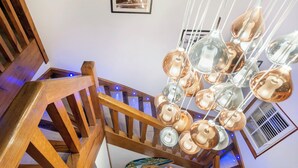 Una scala con ringhiere in legno e un lampadario con diverse lampadine in vetro.